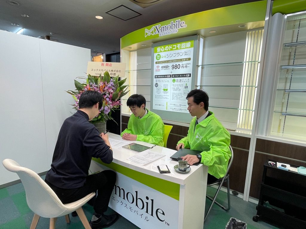 エックスモバイル十日町店でスタッフがお客様に丁寧に説明している様子